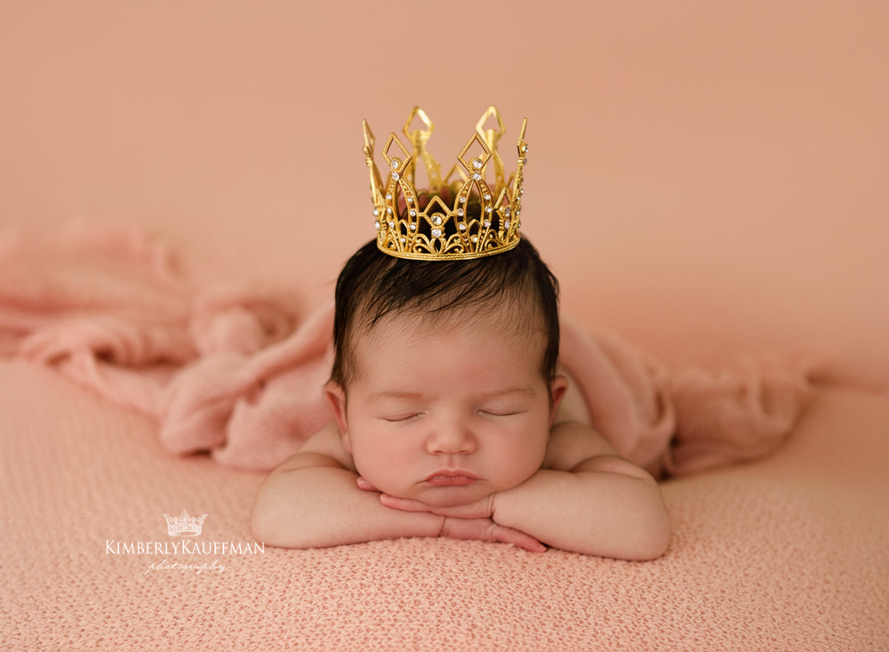 a newborn photo session with baby wearing a crown