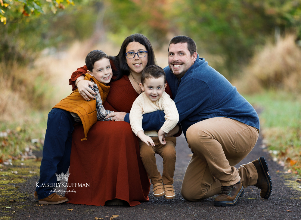 Family cuddling close together with sun flare at golden hour.