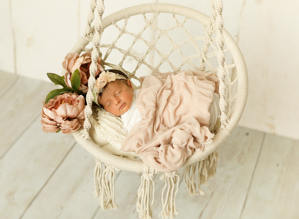 newborn baby girl posed in a boho swing